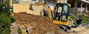 Sewer Flow worker in an excavator digging in a clients yard during a sewer repair