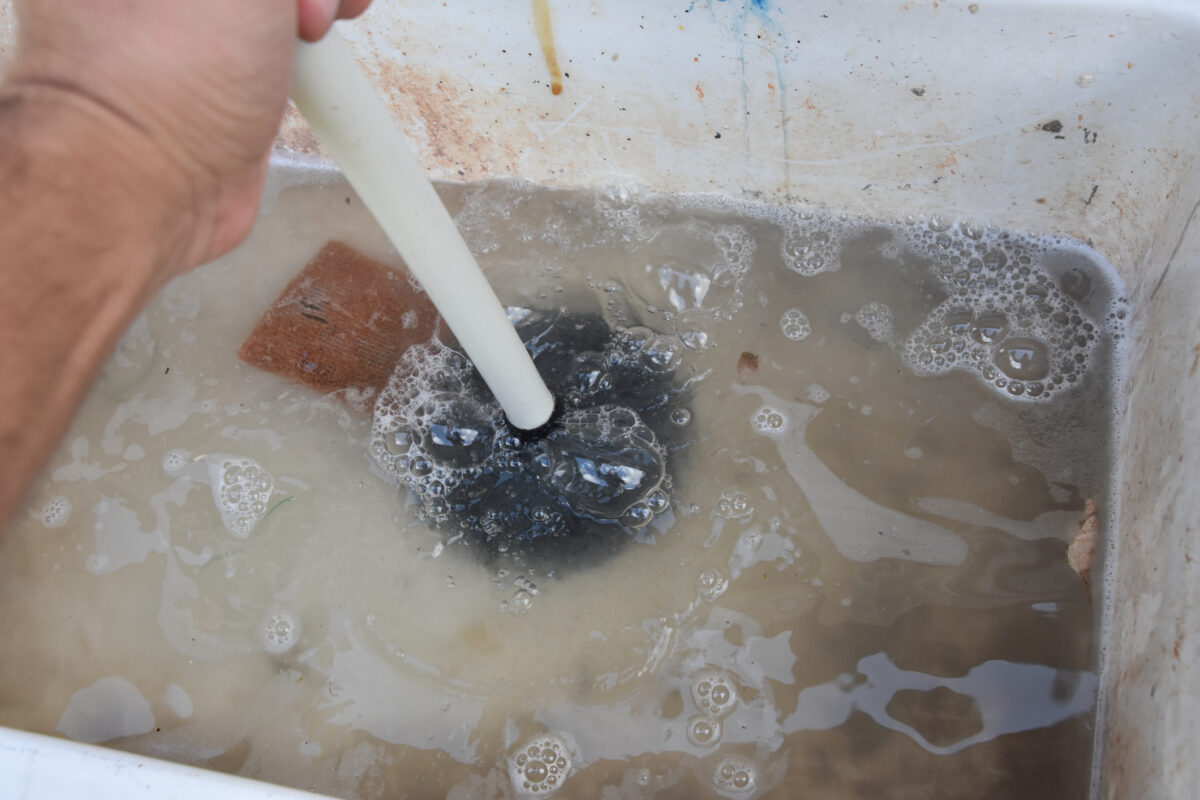 man using a plunger on a clogged basement utility sink